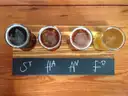 Four beers in small glasses on a wooden board, seen from above