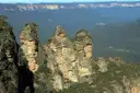 The Three Sisters sandstone rock formation above the forested Blue Mountains valley