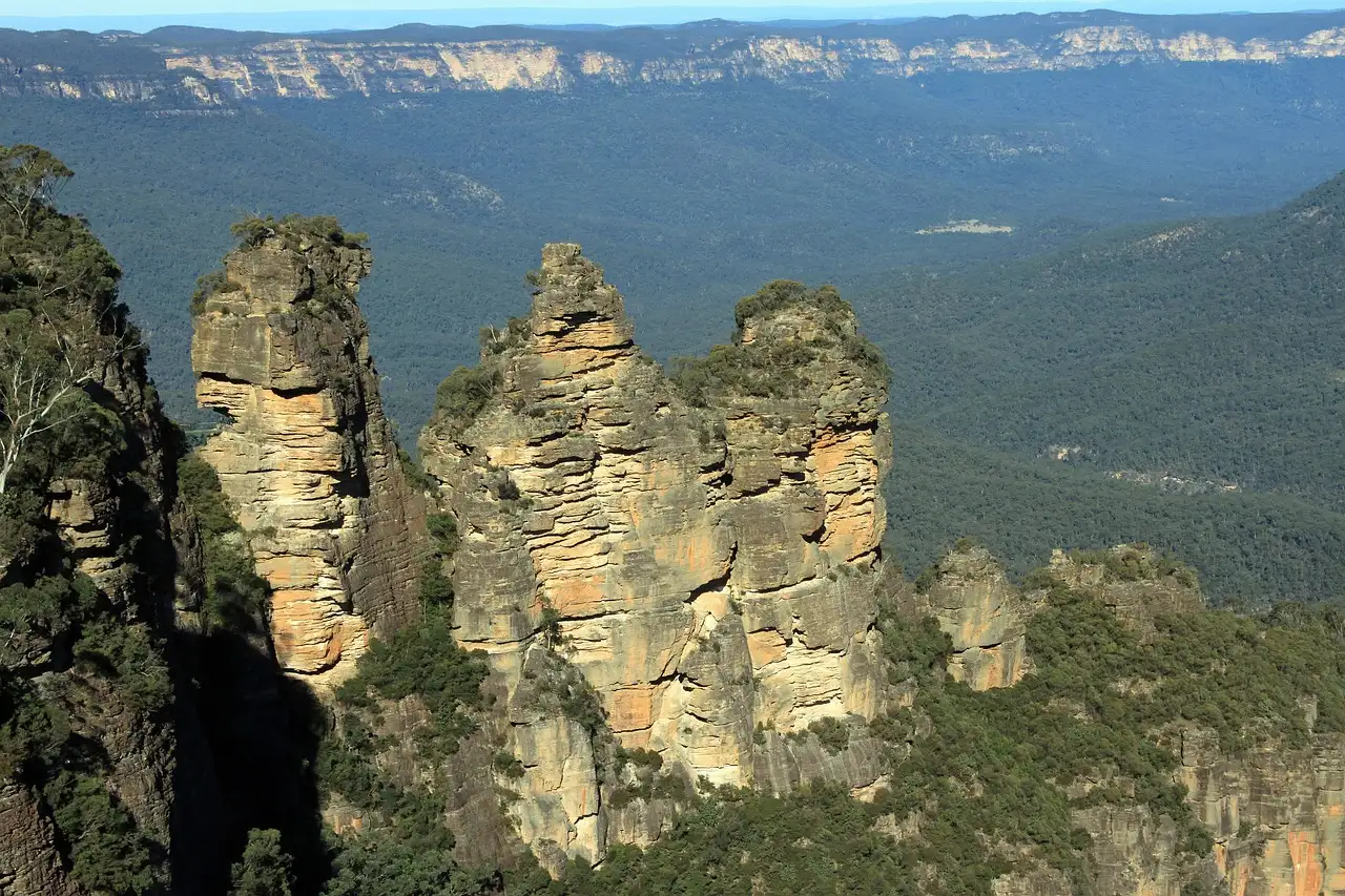 The Three Sisters sandstone rock formation above the forested Blue Mountains valley
