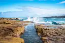 Sandstone rock shelf and breaking waves on the sunny coast near Bondi