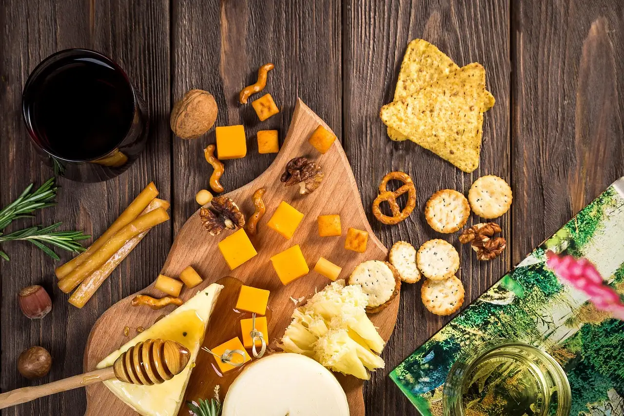 A board of cut cheeses, crackers and honey on a wooden table