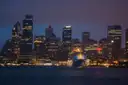 Circular Quay at dusk, with a cruise ship at the terminal and the lit city towers behind