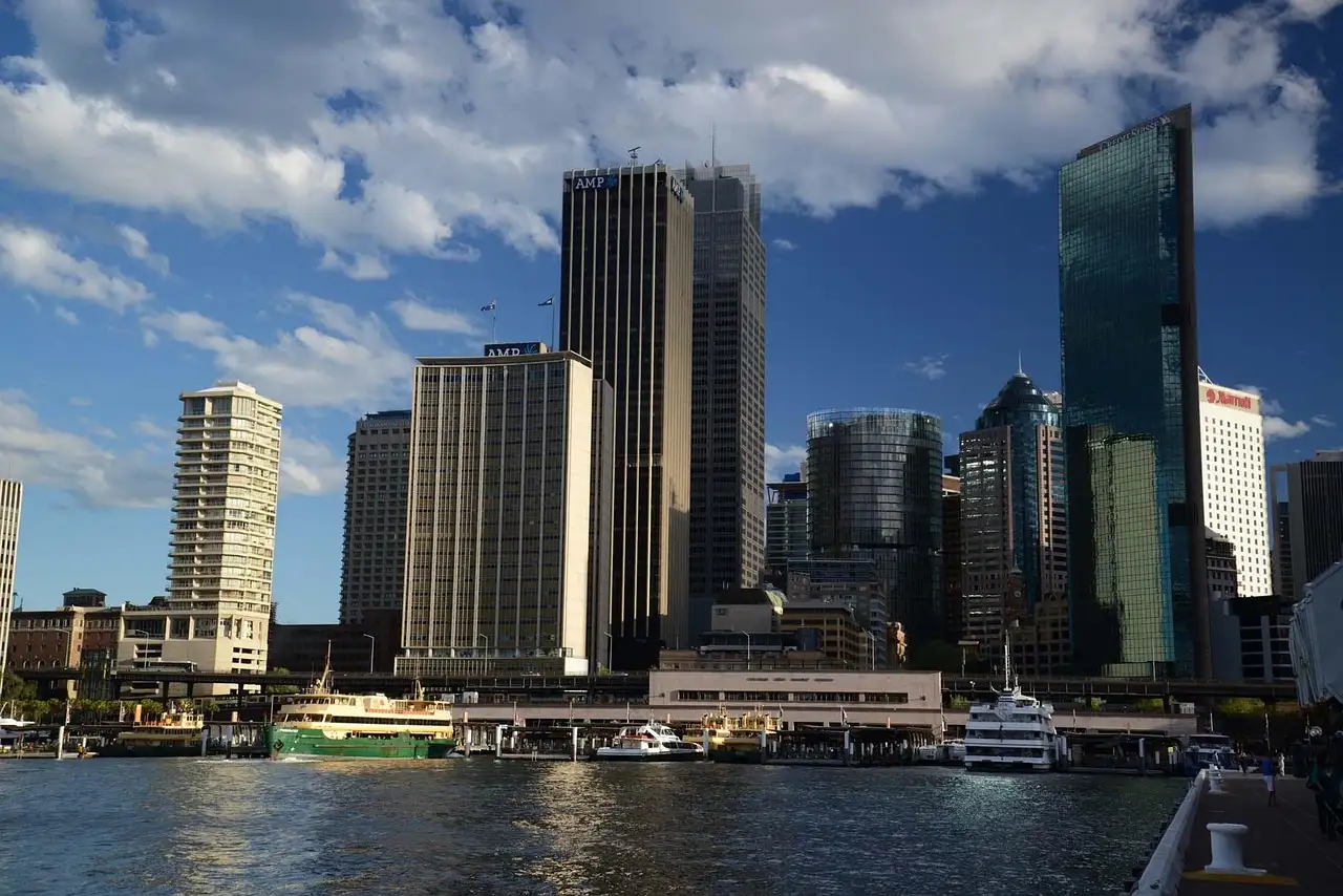 Ferries docked at the Circular Quay wharves in front of Sydney's city towers on a sunny day
