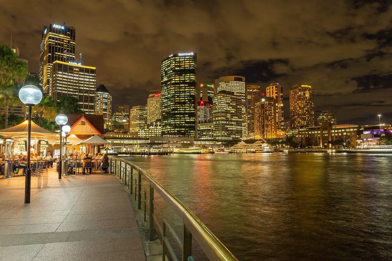 The waterfront promenade at Circular Quay at night, with lamps and lit towers