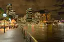 The waterfront promenade at Circular Quay at night, with lamps and lit towers