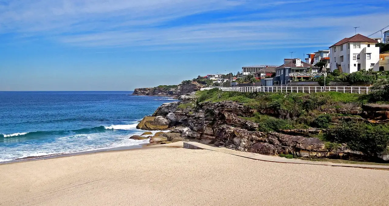 Coogee beach with a grassy headland and houses above the rocks