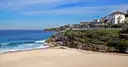 Coogee beach with a grassy headland and houses above the rocks