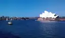 A small cruise boat on Sydney Harbour passing the Sydney Opera House