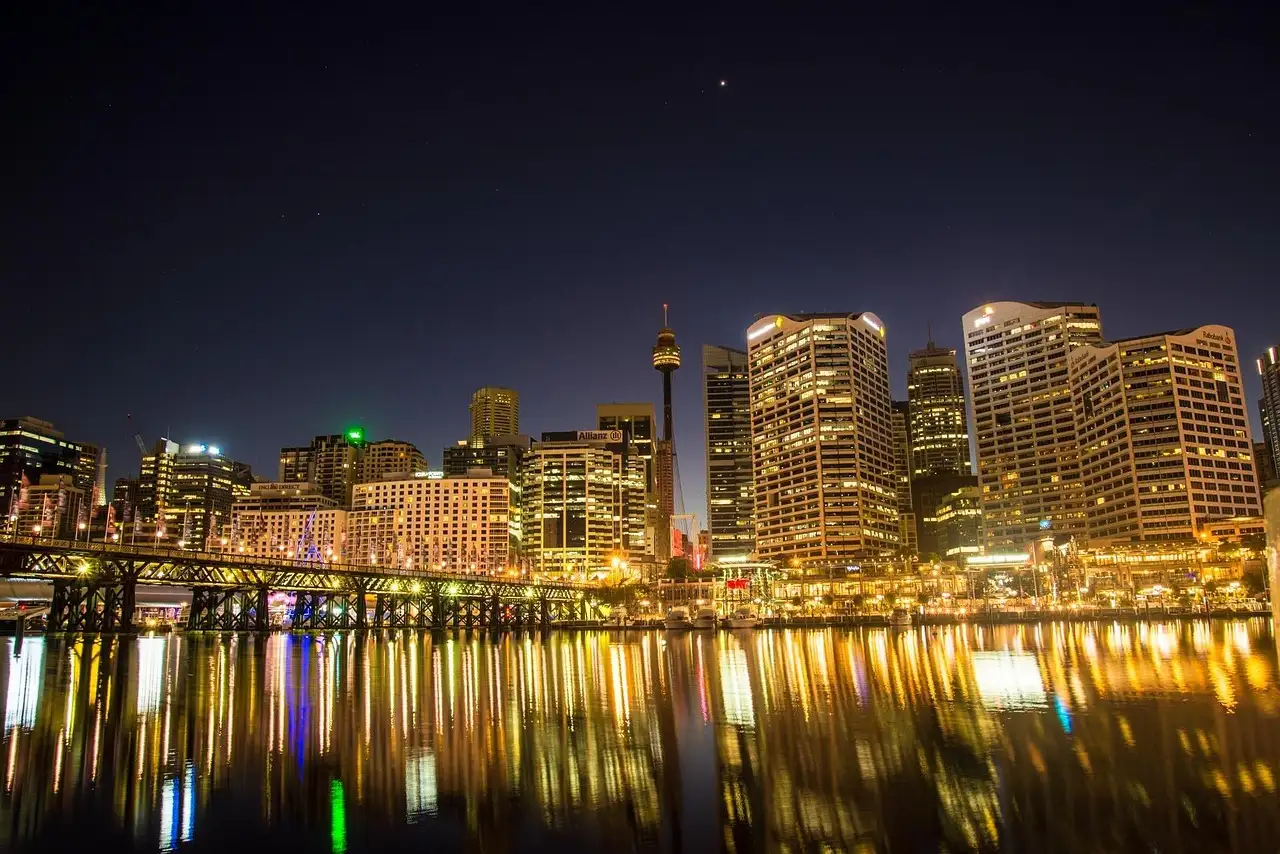 The lit-up city skyline at night, reflected in the water