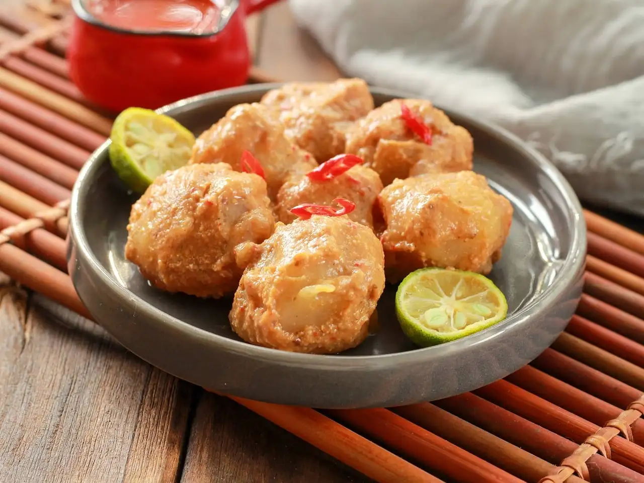 Fried snacks on a plate with lime halves and chilli
