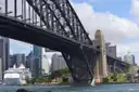 Sydney Harbour Bridge arch and pylon seen from below on the harbour, city towers behind
