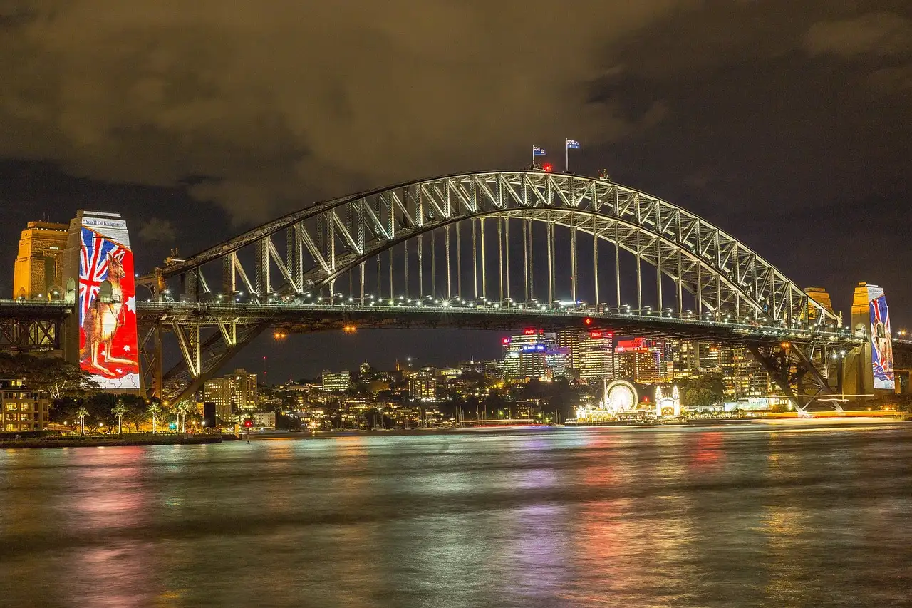 Sydney Harbour Bridge lit up at night with coloured reflections in the harbour