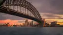 The Sydney Harbour Bridge at sunset, with the Opera House and the city low on the far shore