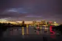 Sydney Harbour at night with boats on the water, the city lights and the Harbour Bridge in the distance