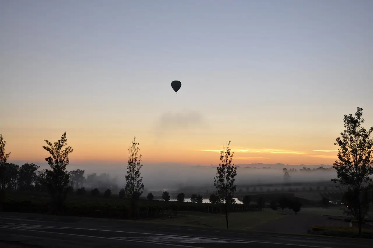 A hot air balloon in the dawn sky over the misty Hunter Valley