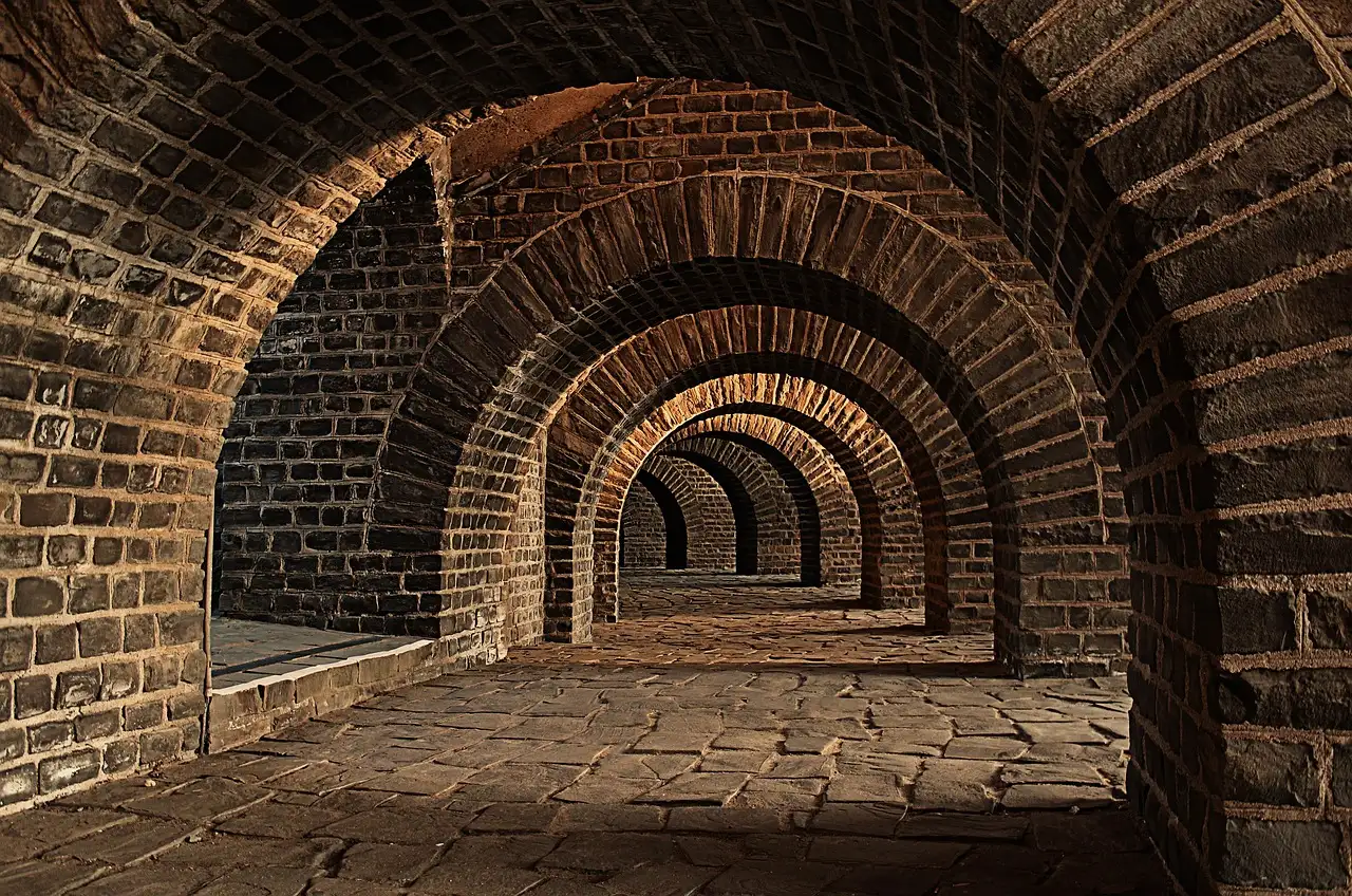 Old brick vaulted cellar with a row of arches in dim warm light