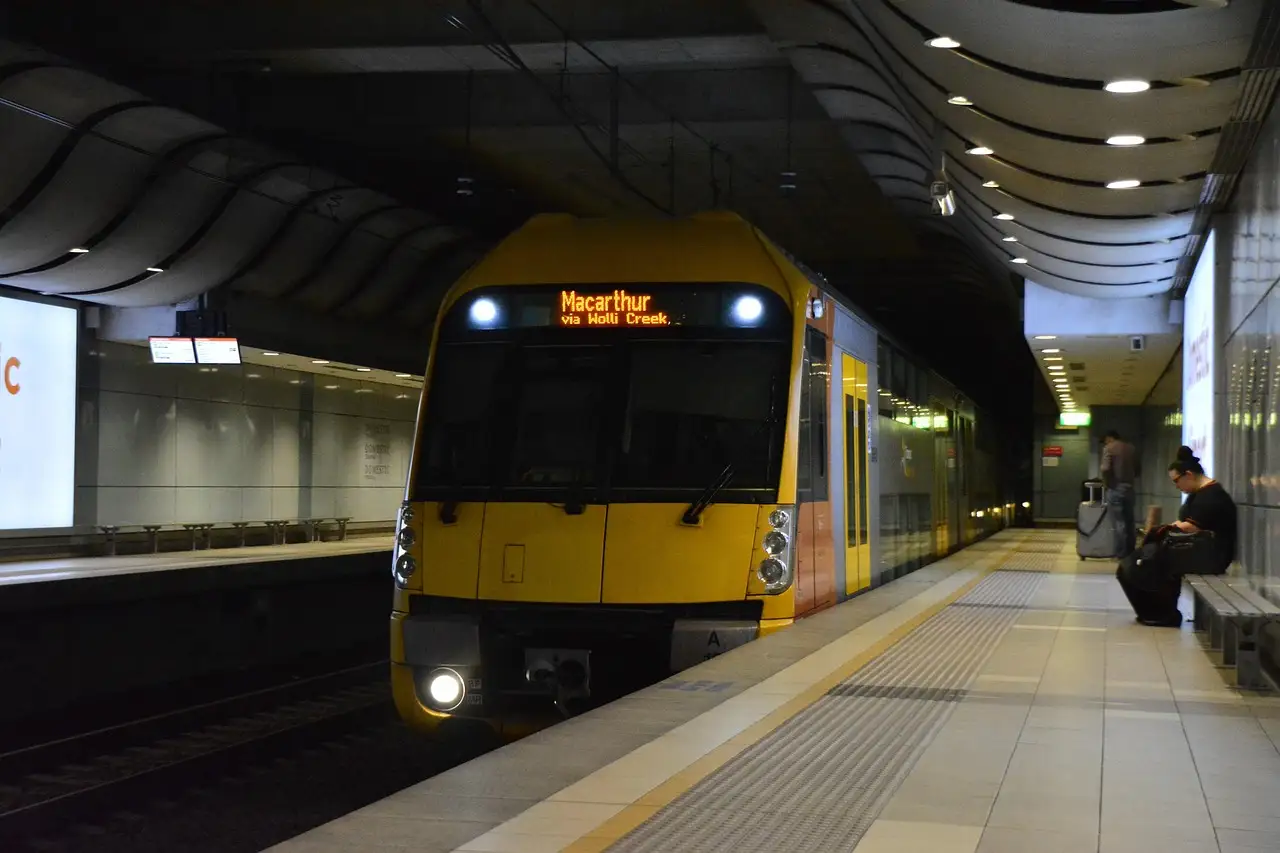 A yellow Sydney suburban train stopped at an underground station platform