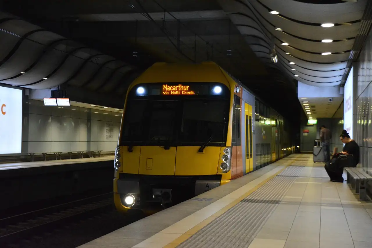 A yellow Sydney suburban train stopped at an underground station platform