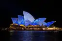 The sails of the Sydney Opera House lit in blue patterns at night