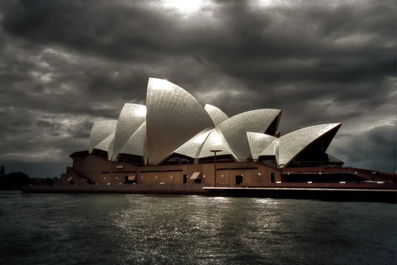 The Sydney Opera House under dark clouds, seen from the water