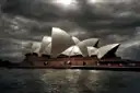 The Sydney Opera House under dark clouds, seen from the water