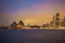 Sydney skyline and Opera House at dusk across the calm harbour
