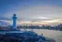 A white lighthouse on a rocky breakwater beside the harbour at Wollongong at dusk