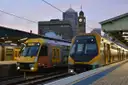 Yellow trains at a Sydney Central Station platform at dusk, with the old clock tower behind