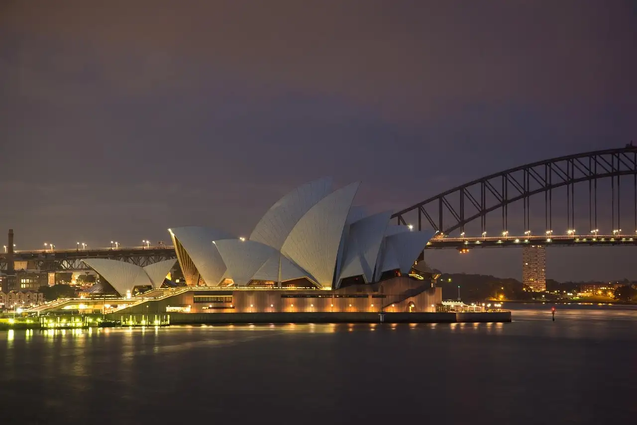 Sydney Opera House and Harbour Bridge at dusk, seen across the harbour from the Mrs Macquarie's Chair side