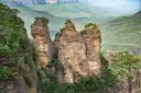 The Three Sisters rock towers above a green forest valley in the Blue Mountains