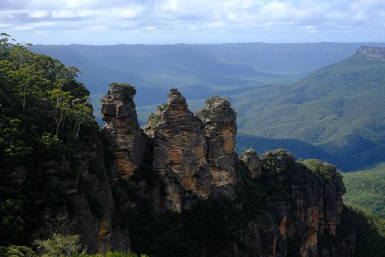 The Three Sisters rock towers on a forested cliff, with the Jamison Valley behind them
