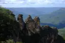 The Three Sisters rock towers on a forested cliff, with the Jamison Valley behind them